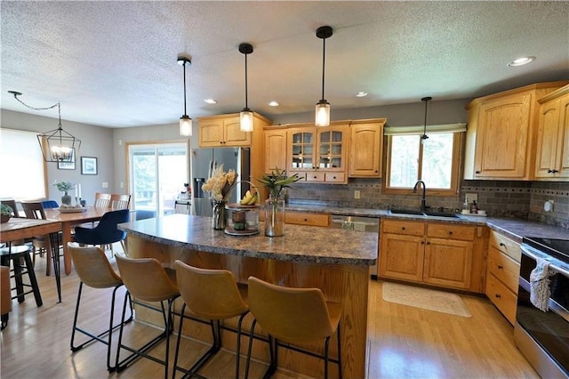 10237 Olker Rd, Hayward, WI 54843 - kitchen with stainless steel appliances, a sink, light wood finished floors, a textured ceiling, and tasteful backsplash