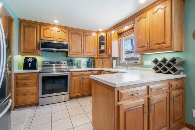 1083 Kenwood St, Green Bay, WI 54304 - kitchen with stainless steel appliances, a sink, light countertops, glass insert cabinets, and brown cabinetry