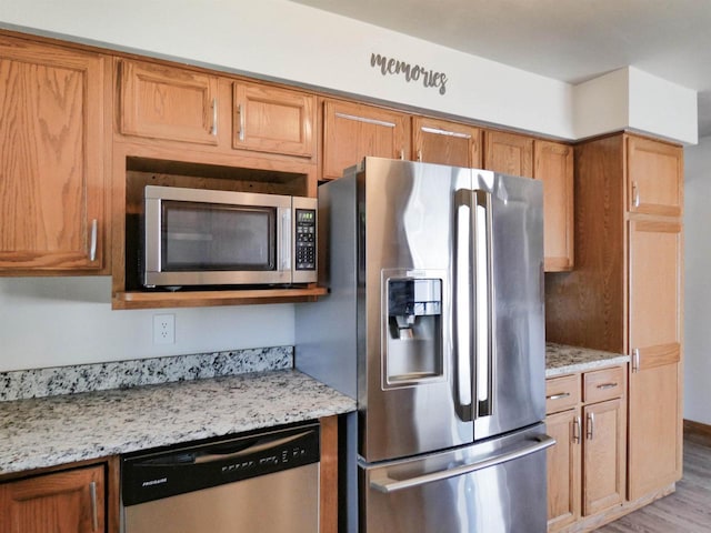 613 S Railroad St, Kimberly, WI 54136 - kitchen featuring appliances with stainless steel finishes, light stone counters, wood finished floors, and brown cabinetry