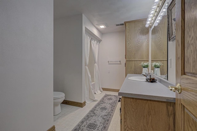 full bathroom featuring toilet, vanity, tile patterned flooring, and baseboards