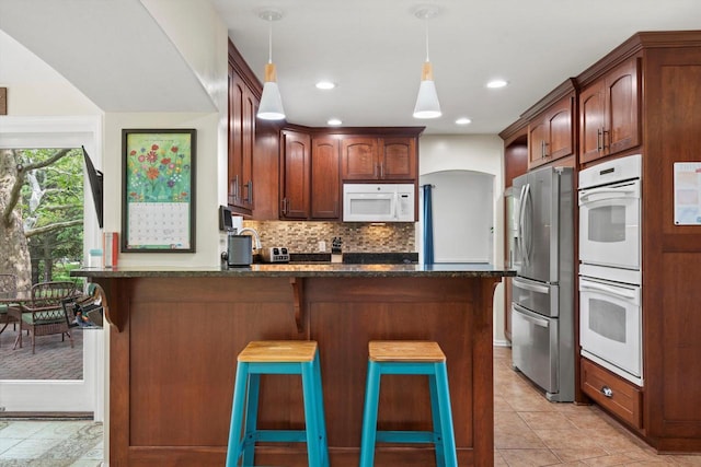 W299S5774 Windcrest Dr, Waukesha, WI 53189 - kitchen with white appliances, a peninsula, backsplash, decorative light fixtures, and a kitchen bar