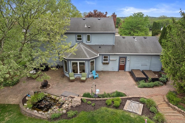 W299S5774 Windcrest Dr, Waukesha, WI 53189 - back of house featuring a patio, a shingled roof, and a chimney