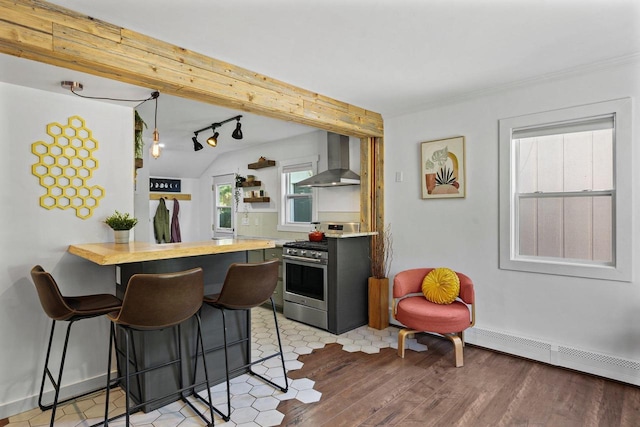 3486 Hargrove St, Madison, WI 53714 - kitchen featuring wall chimney range hood, stainless steel gas stove, a breakfast bar area, light wood-type flooring, and lofted ceiling