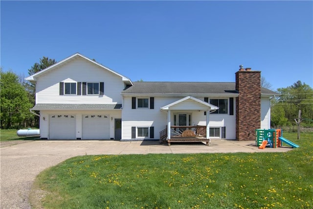 N492 County Road D, Eau Galle, WI 54737 - rear view of house featuring an attached garage, asphalt driveway, a chimney, and a lawn