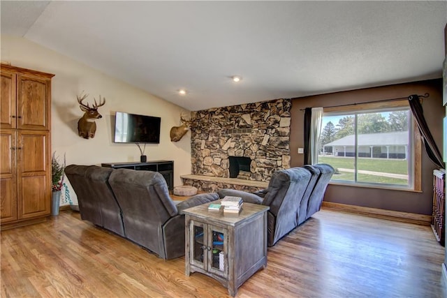 N492 County Road D, Eau Galle, WI 54737 - living area featuring vaulted ceiling, light wood-style floors, a stone fireplace, and baseboards