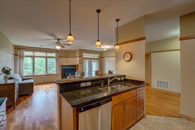 6767 Frank Lloyd Wright Ave Unit 219, Middleton, WI 53562 - kitchen featuring stainless steel dishwasher, a sink, open floor plan, dark stone countertops, and light wood finished floors