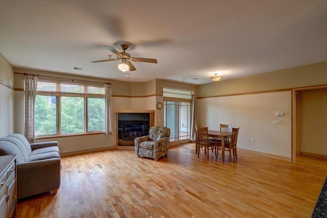 6767 Frank Lloyd Wright Ave Unit 219, Middleton, WI 53562 - living room featuring light wood-style flooring, a glass covered fireplace, a ceiling fan, and baseboards