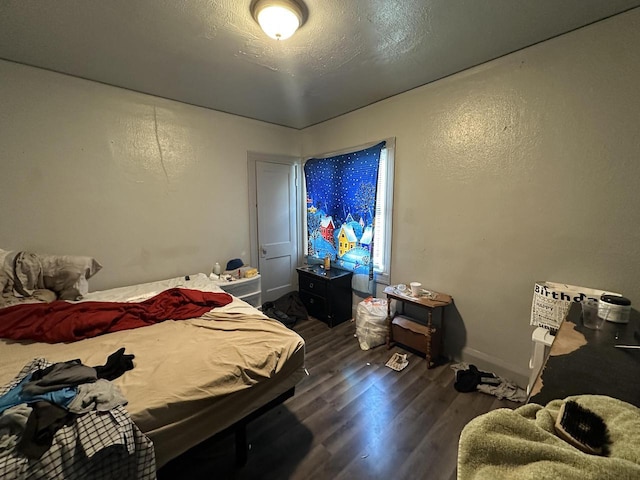 bedroom with dark wood-style flooring, a textured wall, and baseboards