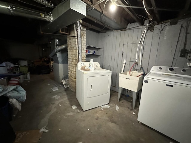 unfinished below grade area with washing machine and clothes dryer, a sink, and heating unit