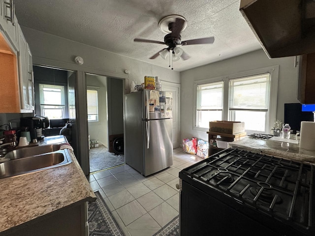 kitchen featuring freestanding refrigerator, black gas range, a sink, ceiling fan, and plenty of natural light