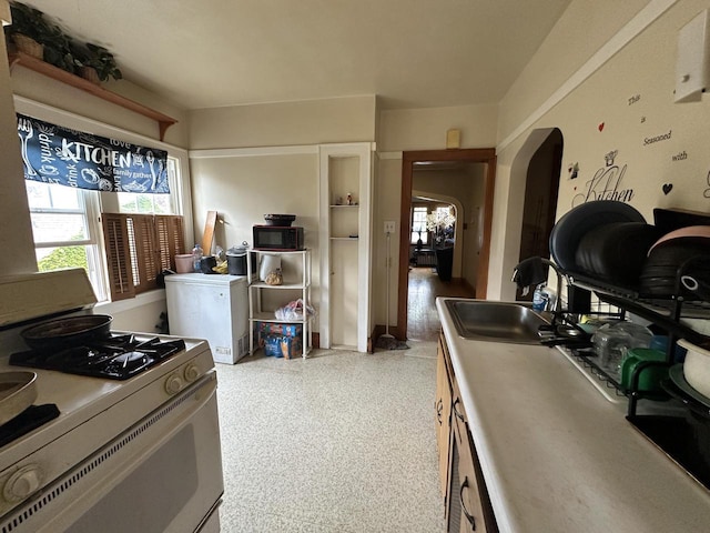 5733 W Philip Pl, Milwaukee, WI 53216 - kitchen featuring white gas stove, arched walkways, black microwave, and a sink