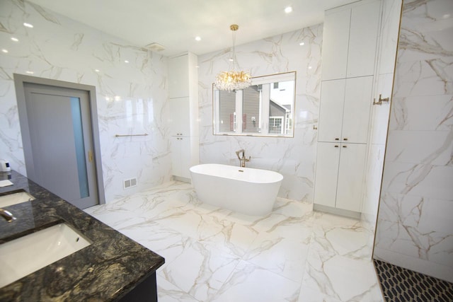bathroom with marble tiled flooring, a chandelier, a freestanding bath, and vanity