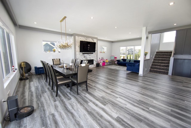 dining area with wood finished floors, recessed lighting, stairway, a chandelier, and a premium fireplace