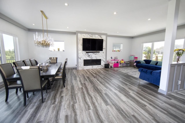 dining area featuring wood finished floors, a high end fireplace, recessed lighting, a chandelier, and baseboards