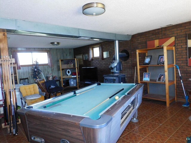 8305 Half Moon Dr, Iron River, WI 54847 - recreation room featuring brick wall, a wood stove, a textured ceiling, billiards, and healthy amount of natural light