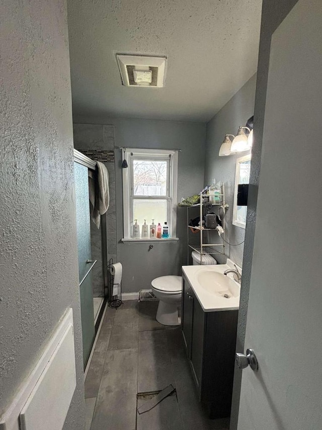 8210 W Winfield Ave, Milwaukee, WI 53218 - bathroom with a shower stall, vanity, toilet, a textured ceiling, and wood finished floors
