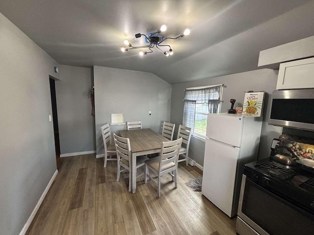 8210 W Winfield Ave, Milwaukee, WI 53218 - dining area with baseboards, wood finished floors, lofted ceiling, and a chandelier