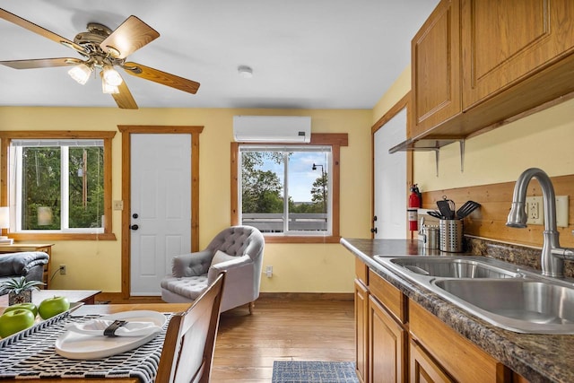 N5101 Hemlock St, Poynette, WI 53955 - kitchen featuring a sink, a wall unit AC, baseboards, light wood finished floors, and dark countertops