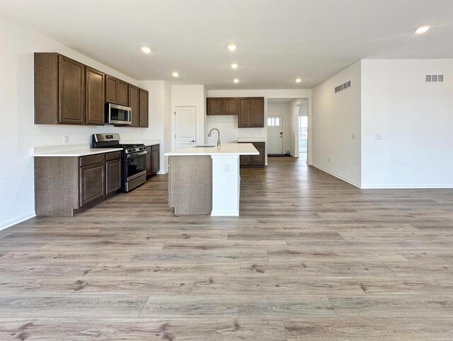 2833 Jackson St, Stoughton, WI 53589 - kitchen featuring stainless steel appliances, a sink, light wood-type flooring, light countertops, and a center island with sink