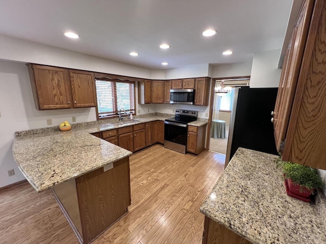 1012 Silent Sunday Ct, Racine, WI 53402 - kitchen featuring appliances with stainless steel finishes, a sink, a peninsula, light wood-style flooring, and healthy amount of natural light