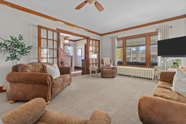 61 N Grand St, Markesan, WI 53946 - living room featuring radiator heating unit, ornamental molding, stairs, a ceiling fan, and carpet