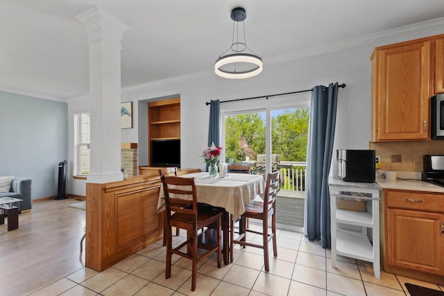 dining space with decorative columns, plenty of natural light, ornamental molding, and light tile patterned flooring