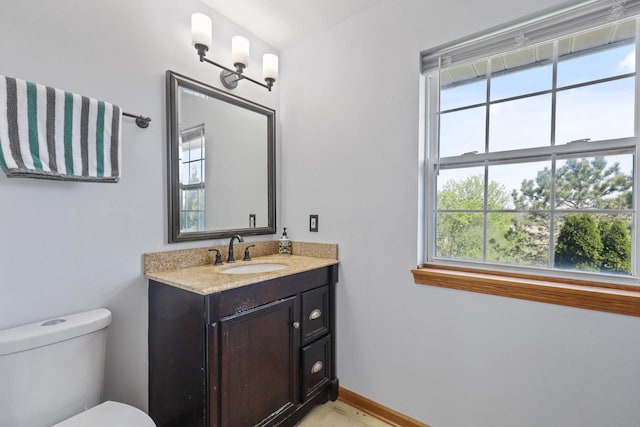 half bathroom with toilet, vanity, and baseboards