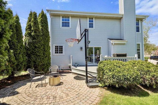 rear view of house featuring a wooden deck, a patio area, and a chimney