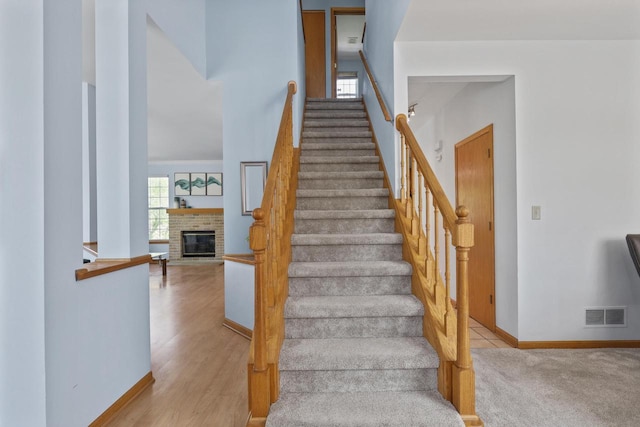 staircase with a fireplace, baseboards, and a high ceiling