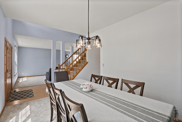 dining area with a chandelier, stairway, wood finished floors, carpet, and baseboards