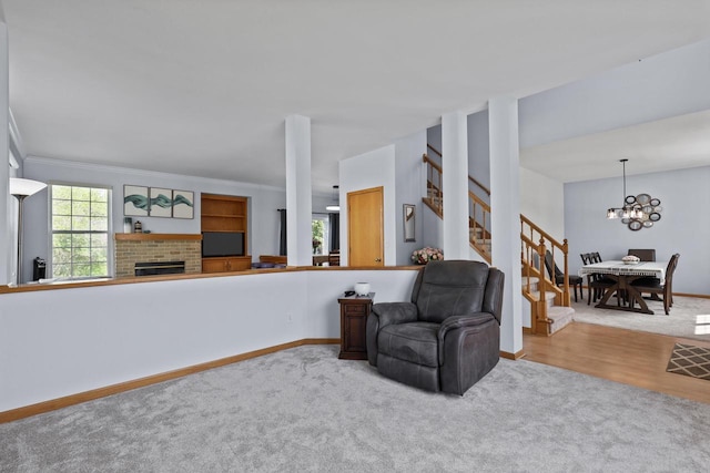living area featuring stairway, carpet flooring, a fireplace, a chandelier, and baseboards