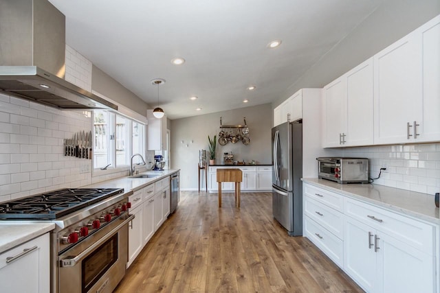 5402 Comanche Way, Madison, WI 53704 - kitchen featuring appliances with stainless steel finishes, a sink, wall chimney range hood, white cabinets, and decorative backsplash