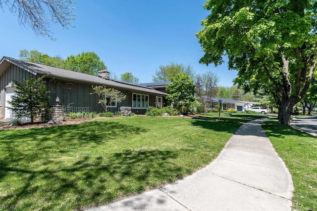 5402 Comanche Way, Madison, WI 53704 - view of home's exterior with board and batten siding, a chimney, a lawn, and a garage