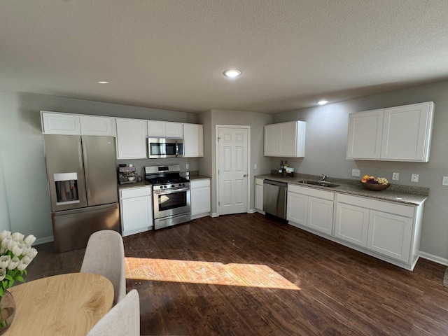 708 E Maple Beach Dr, Edgerton, WI 53534 - kitchen featuring appliances with stainless steel finishes, baseboards, a sink, dark wood-style floors, and white cabinetry
