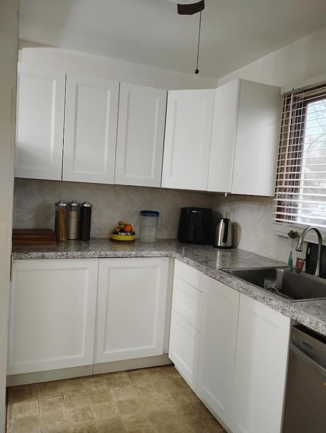 kitchen with stainless steel dishwasher, a sink, and white cabinetry
