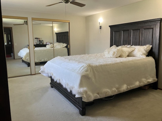 bedroom with light colored carpet, ceiling fan, and two closets