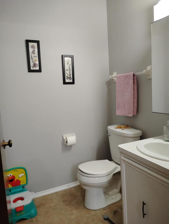 bathroom featuring toilet, vanity, baseboards, and tile patterned floors