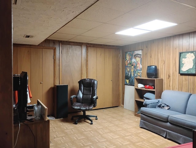 office area with wooden walls and a drop ceiling