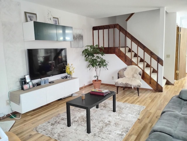 living room featuring wood finished floors, stairs, and baseboards