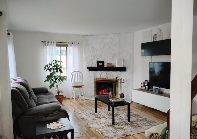 living room featuring a stone fireplace and wood finished floors