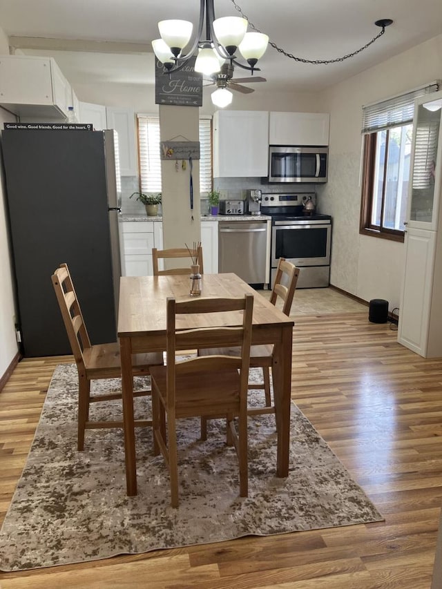 dining room with a chandelier, light wood finished floors, and baseboards