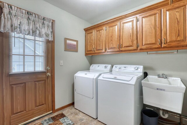 clothes washing area with separate washer and dryer, cabinet space, and baseboards