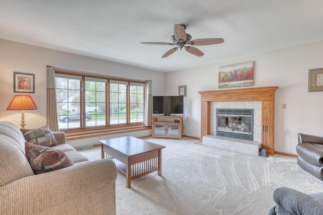 living room with light colored carpet, baseboards, a ceiling fan, and a tile fireplace