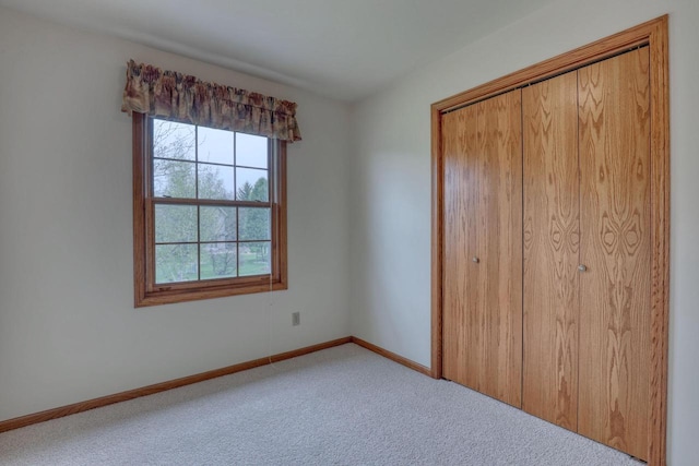 unfurnished bedroom with carpet, a closet, and baseboards