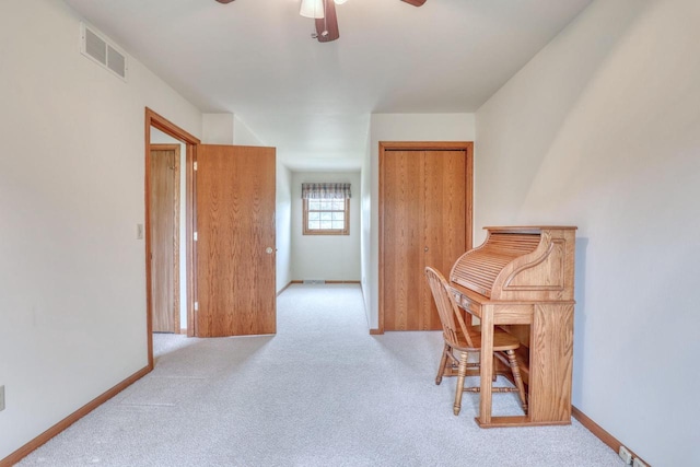 carpeted office space with ceiling fan and baseboards