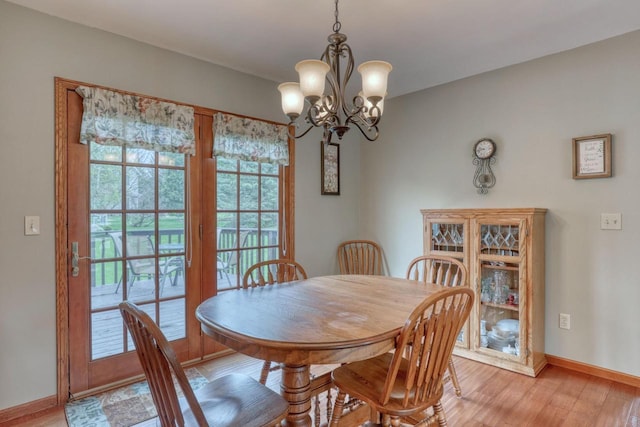 dining space featuring a chandelier, baseboards, and light wood finished floors