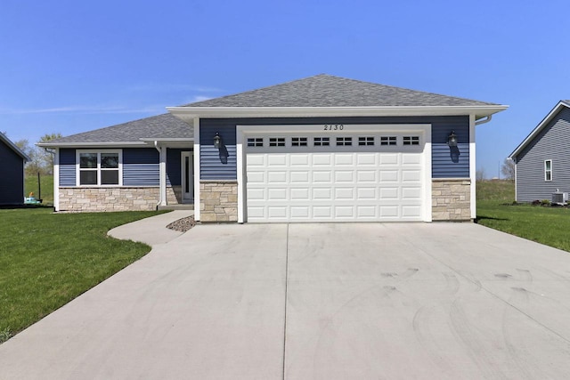 2130 90th St, Sturtevant, WI 53177 - view of front facade with stone siding, a front lawn, concrete driveway, a garage, and roof with shingles