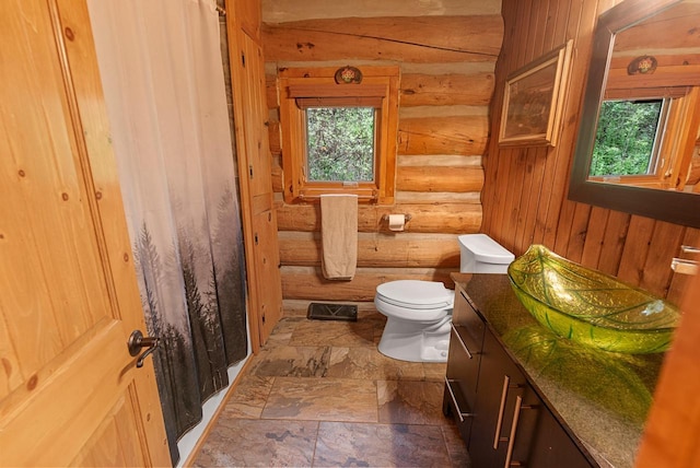 644 County Highway K, Hartford, WI 53027 - bathroom featuring log walls, healthy amount of natural light, toilet, stone finish flooring, and vanity