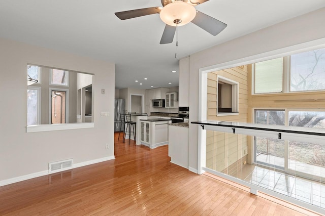 unfurnished living room featuring healthy amount of natural light, wood-type flooring, baseboards, ceiling fan, and recessed lighting