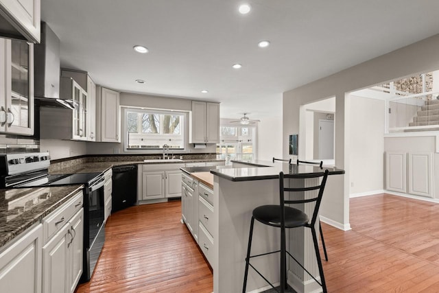 kitchen featuring stainless steel electric range oven, dishwasher, a breakfast bar, a sink, and glass insert cabinets